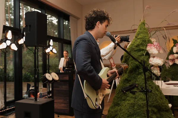 Julian Moss performing at the microphone with PA speakers and event lighting