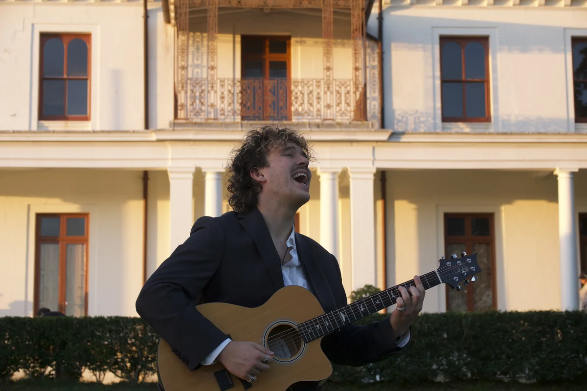 Julian Moss singing and playing acoustic guitar at Strickland House